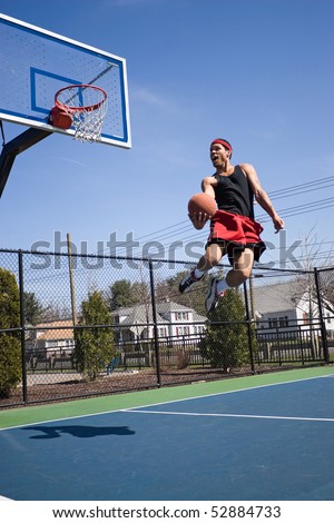 A young athlete flying through the air towards the basketball hoop for a lay up or slam dunk.