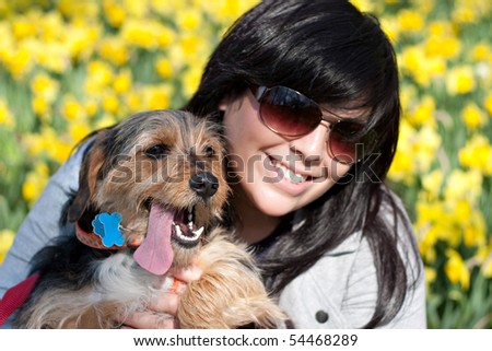 A cute terrier mix breed pup in the arms of a beautiful pet owner. Shallow depth of field with sharp focus on the dog\'s nose.