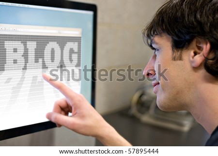 stock photo : A young main pointing at a computer screen that reads BLOG in the web browser window.