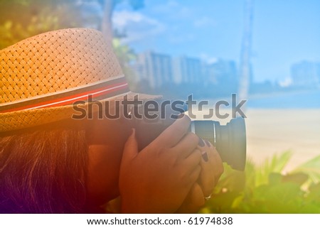 Woman photographer shooting with her digital camera outdoors in a tropical area with abstract color glow.
