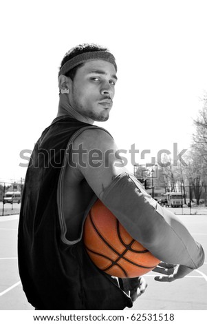 A young basketball player on the court at the park in black and white and the ball in selective color.