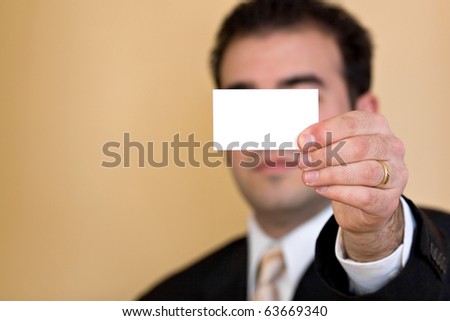 Close up of a man holding an empty business card up.  Plenty of copy space for your logo or design.  Shallow depth of field.
