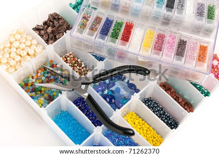 An organizer full of multi colored beads and tools for making jewelry and crafts.