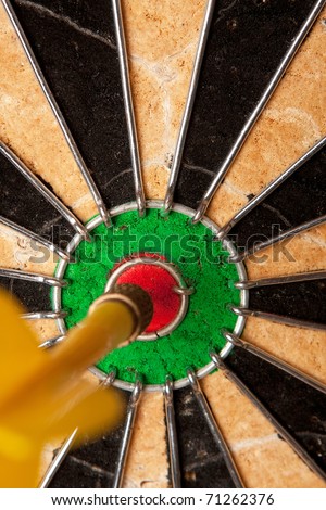 Close up of a dart that has nailed a bulls eye in the center of the dart board. Shallow depth of field.