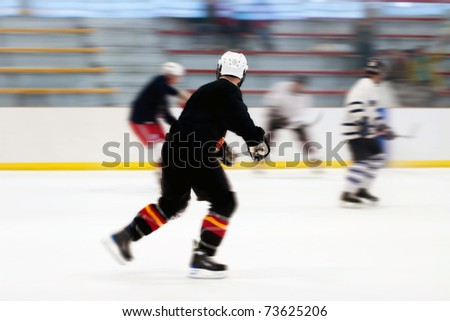 Panned motion blur of two hockey players skating down the ice rink.  Shallow depth of field.
