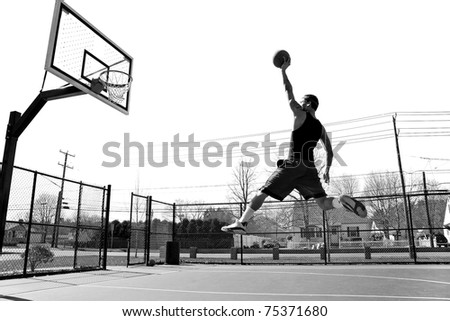 A young basketball player flying towards the rim for a slam dunk.