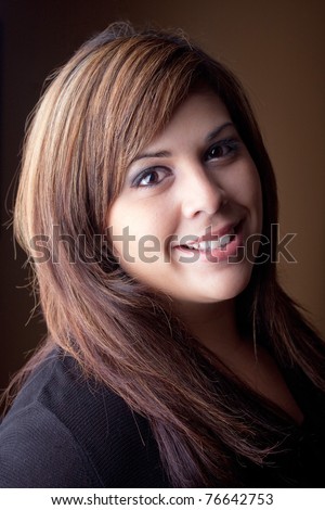 A beautiful young Latin woman with a smile on her face and highlighted hair.