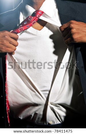 A young African American business man ripping his shirt open to reveal the t-shirt beneath. Add your text or artwork to easily customize the message.