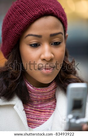 A young woman text messaging or checking email on her wireless phone. Shallow depth of field.