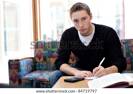 A young man working on his science physics or math homework in an educational setting.