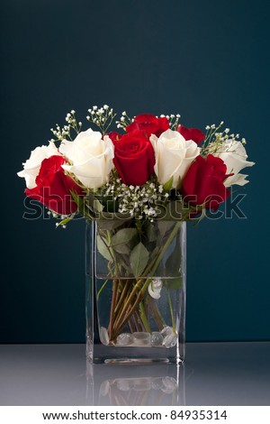 An arrangement of beautiful red and white roses with baby's breath in a clear glass vase.