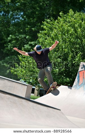 Action shot of a skateboarder going up a concrete skateboarding ramp at the skate park.