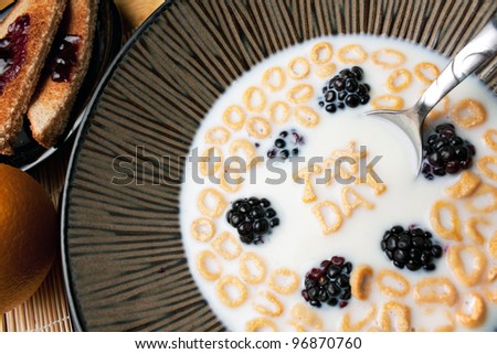 Bowl of cereal with blackberries and letter shaped pieces spelling the words TAX DAY floating in a milk.