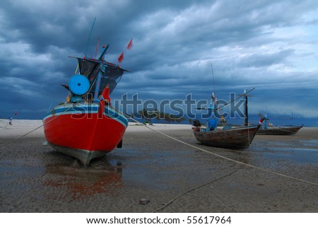 A view of a red Thai fishing boat floating in cloudy sky.
