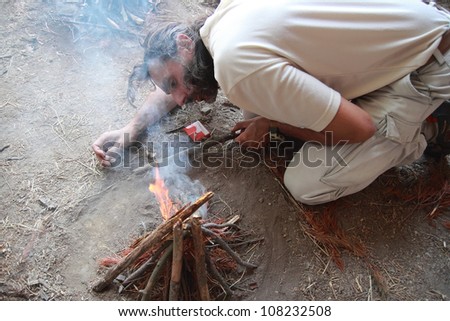 caucasian man lighting a fire camp
