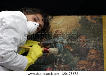 restorer at work on damaged ancient painting