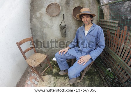 poor caucasian farmer siting in a shabby interior