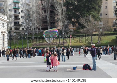 MADRID - MARCH 2: Street artist makes soap bubbles for children in front of the Royal Palace of Aranjuez on March 2, 2013 in Madrid, Spain