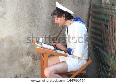 man in old student costume writing with a feather