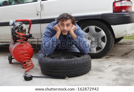 Changing a tire, pensive man and spare wheel