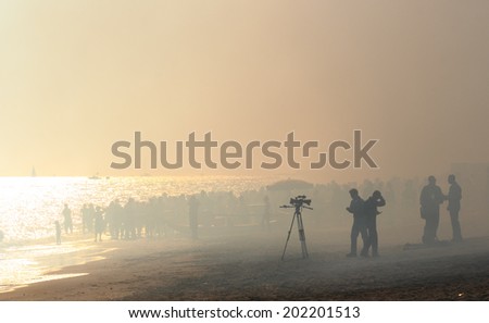 ROME, ITALY - JUNE 28, 2014:  People on Ostia beach during the Rome International Air Show , heavy smoke cover the area after the Frecce Tricolori, the Italian aerobatic team performance