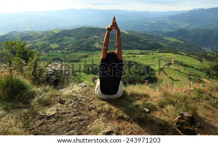 man practicing Yoga at the top of a mountain