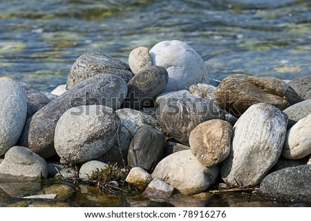 pile of gray river rocks over an out of focus river background