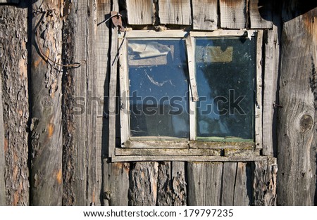 The old peeled hovel. Lop-sided window. Texture of old wooden boards.