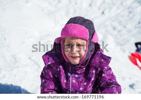 The little girl cries sitting on snow.Playing in snow