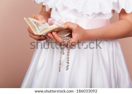 Girl praying with her hands clasped and white dress. First Communion