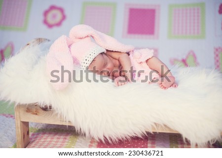 Eight day old newborn baby wearing bunny ears and a bunny tail diaper cover. she is sleeping on his stomach in a basket.