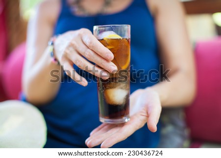 Woman hand holding fresh Cola with ice cubes