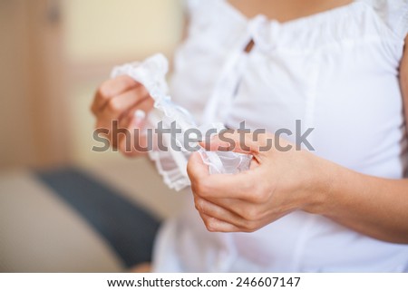 Woman holds two garters which are traditionally worn on the bride\'s thigh during the wedding ceremony and reception.