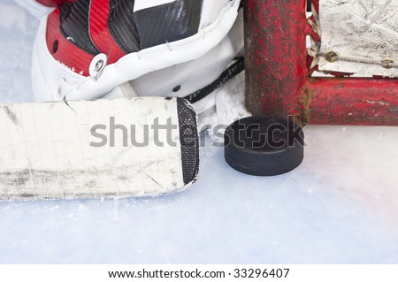 Close-up on hockey puck with goalie and net post