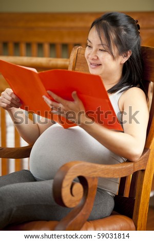 Pregnant woman reading folder information.