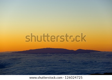 Sunset above the clouds. The view of the island of Maui, from the Mauna Kea volcano on the Big Island, Hawaii.