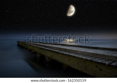 The Moon and stars above a wooden pier.