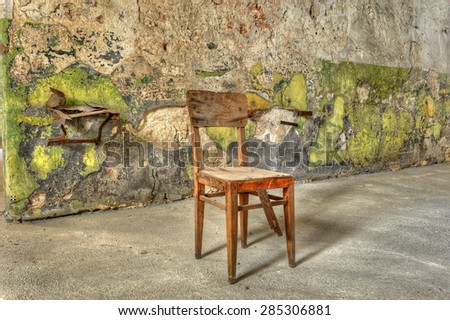Old wooden chair against a filthy wall in an abandoned prison. Ready for the interview?