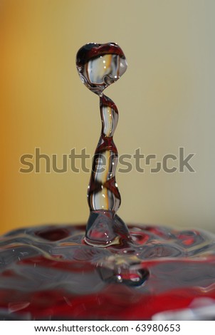 Water droplet rebound or splash with red reflections. One of a series with the same title.