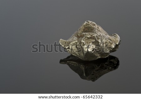 Metallic meteorite on a black reflective surface. This is from the \