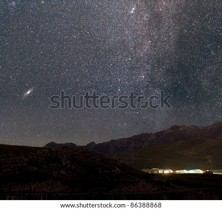 The stars of the Milky Way over an Alpine village. Andromeda galaxy to the left.