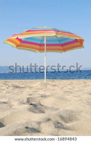 Color umbrella at big beautiful sand beach against blue sky and sea