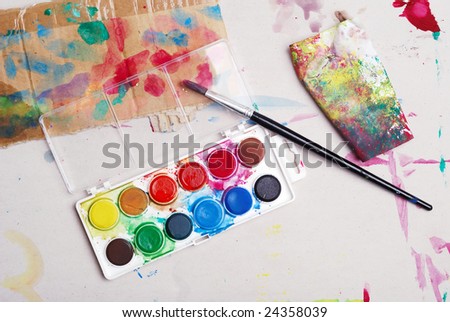 Dirty watercolor paints set with brush and papers