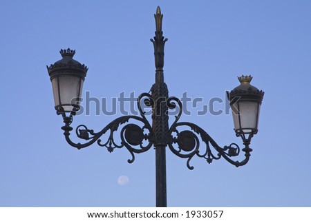 Traditional Madrid lamp post with blue sky and moon