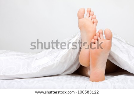 Close up of two feet in a bed