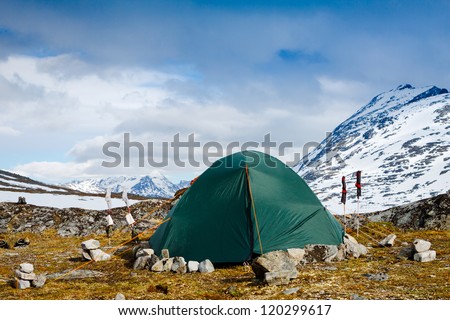 Camping with a tent in Alps with snow capped mountains