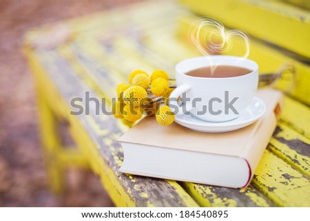 love and tea. heart silhouette from steaming hot cup with book and flowers