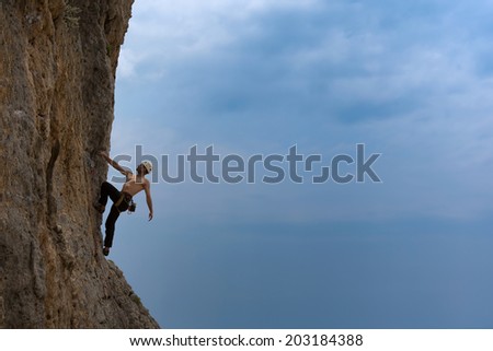 A silhouette of man climbing on rock, mountain at sunset. Adrenaline, strenght, ambition