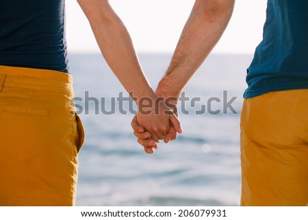 Love - romantic couple holding hands, beach sunset. Young woman and man in love walking hand in hand on beach.