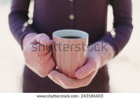 Female hands  in mittens holding cup with hot  tea or coffee. Winter and Christmas time concept